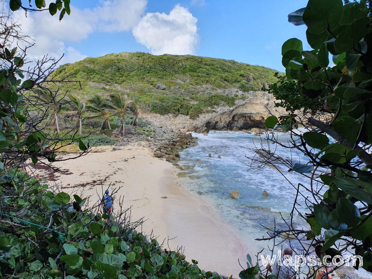 Fenêtre sur Anse du Coq depuis le sentier qui descend entre les rochers
